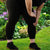 Femme en leggings noirs se tenant le genou dans un jardin fleuri, mettant en avant le confort des socquettes larges