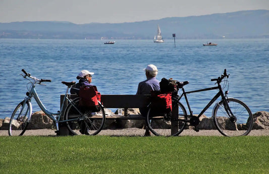 Un couple de senior est assis sur un banc pour regarder la mer avec les vélos derrières eux