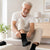 Homme senior en train d'enfiler des chaussettes confort senior homme femme dans un salon lumineux.