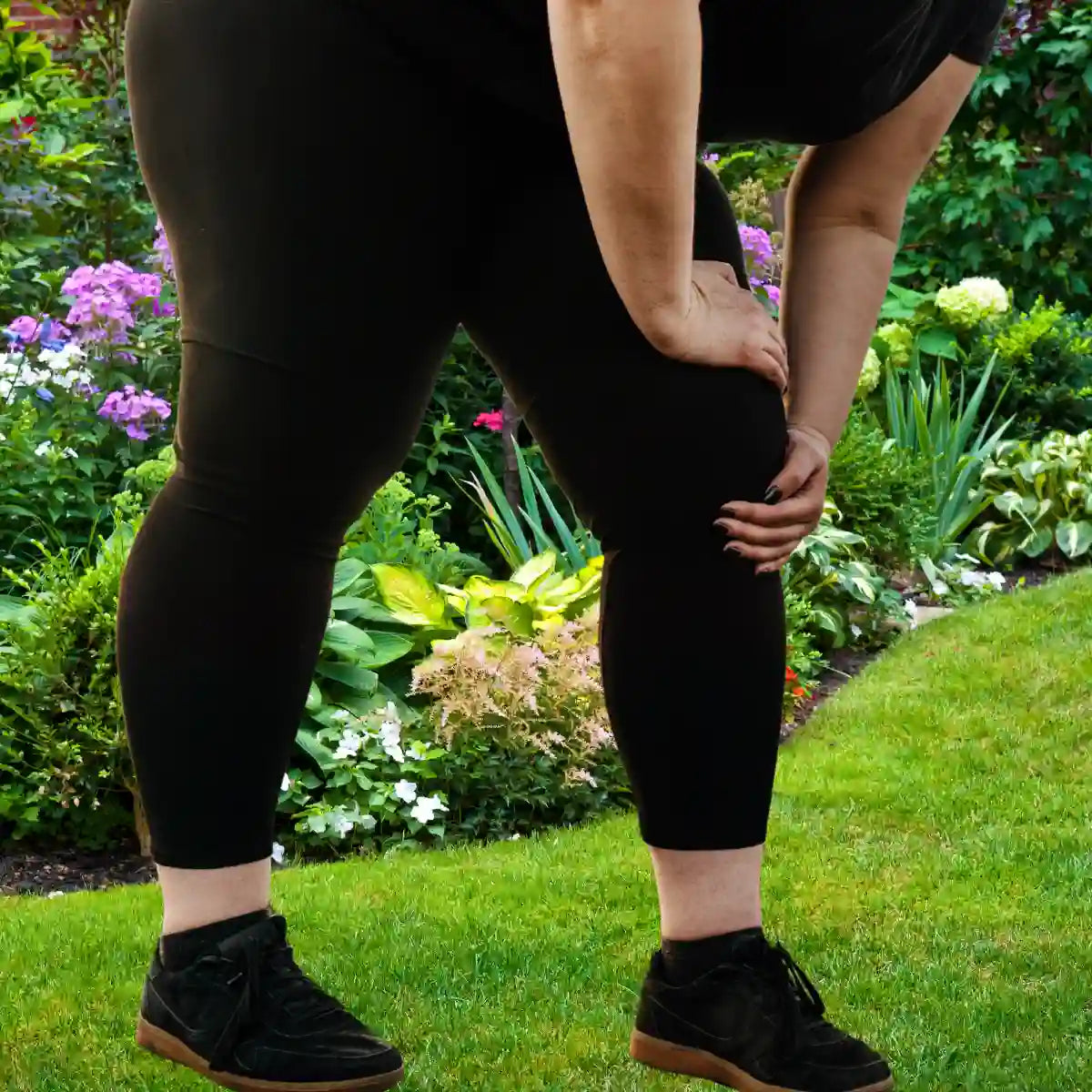 Femme portant des chaussettes respirantes anti transpiration, en train de s'étirer dans un jardin fleuri.